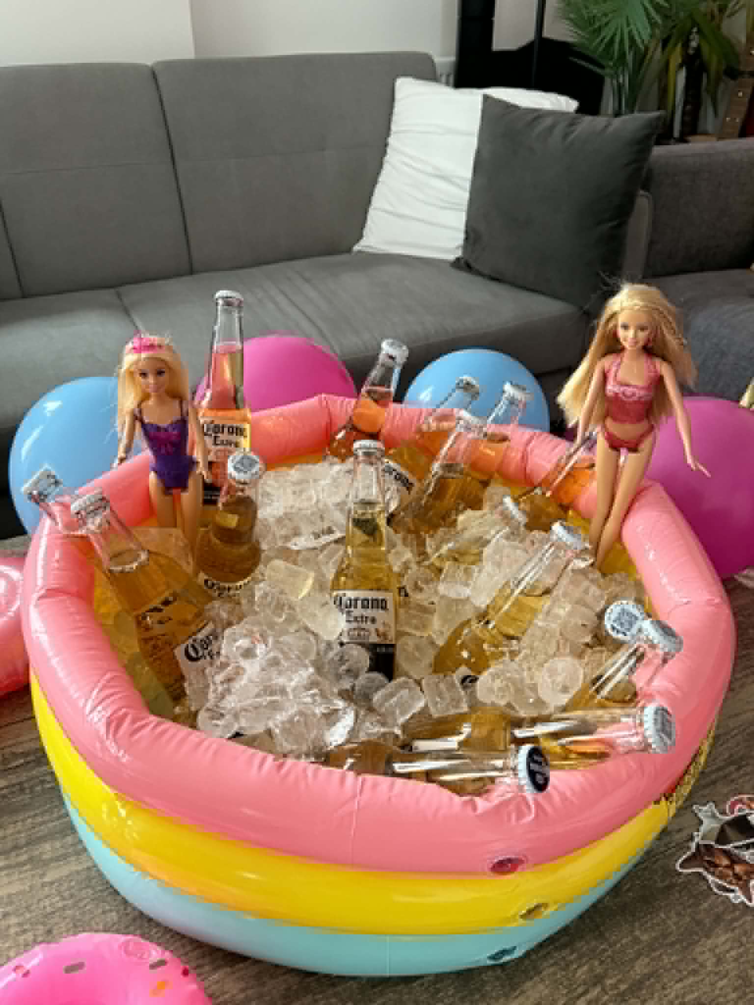 Doll-themed pool party drinks display with bright balloons and decorations.