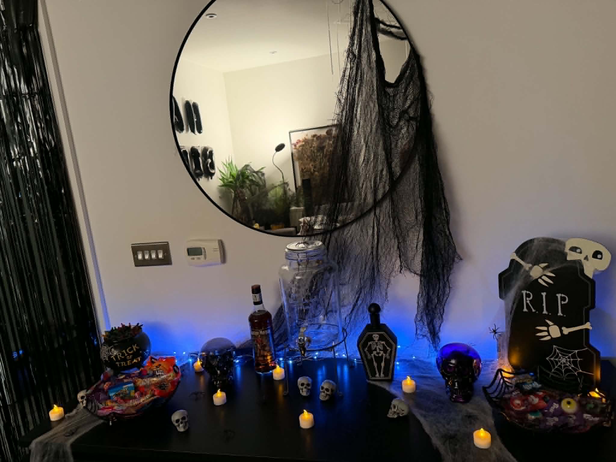 Halloween treat table with candles, themed props, and spooky decorations.